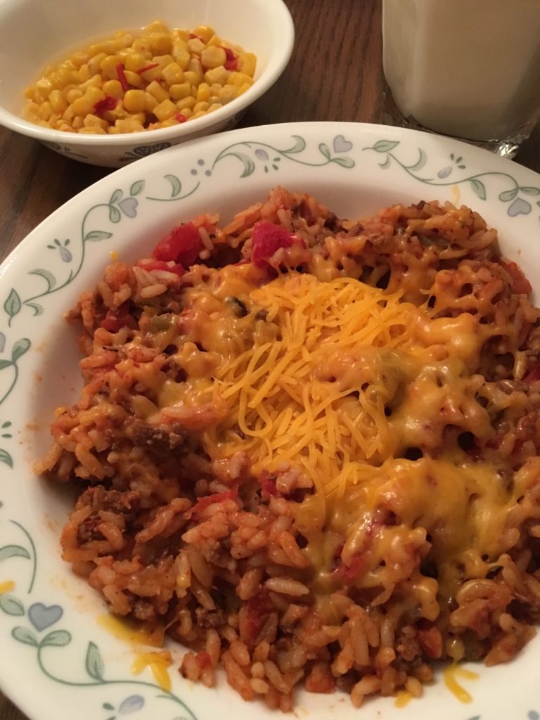 Rice, tomato, and meat hotdish on a plate with cheese melted on top